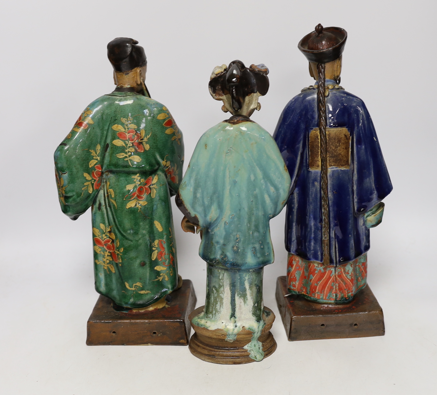 A pair of large 19th century Chinese Shiwan or Guandong pottery figures of Mandarins, and a similar figure of a lady, tallest 32.5cm